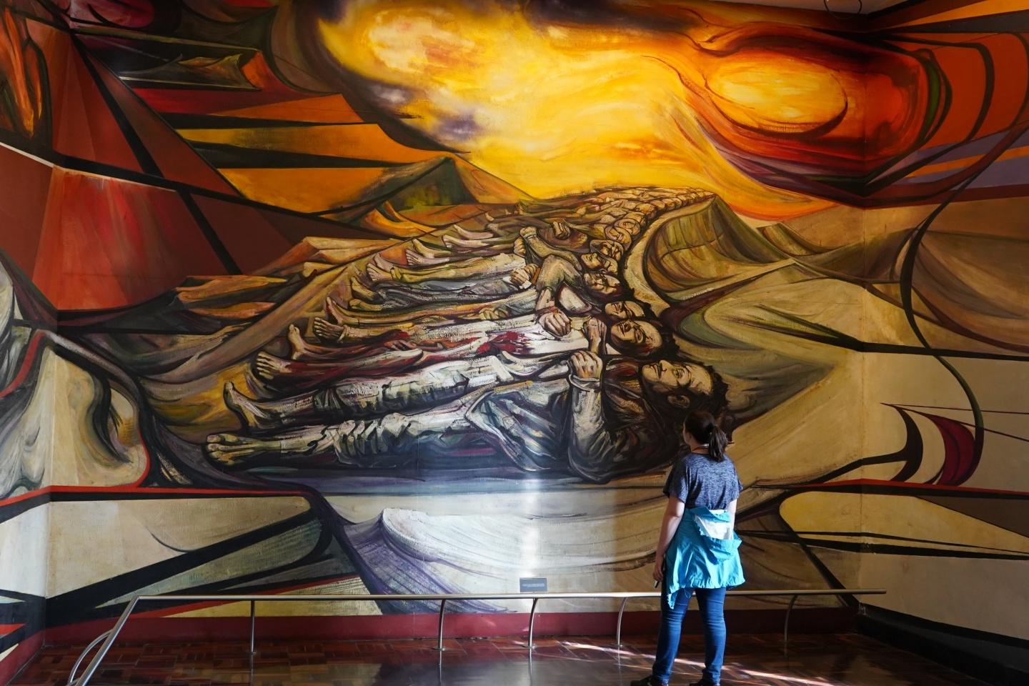 一个学生在展览会上凝视着一幅巨大的西班牙壁画 
